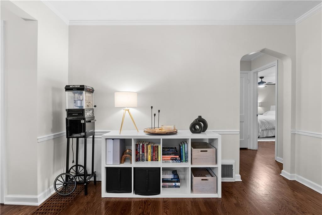 Furnished room with a white cubby bookshelf, vintage popcorn machine, and arched doorway to a bedroom.