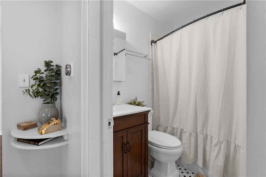 Bathroom with a dark wood vanity, white shower curtain, and black-and-white hexagonal floor tile.