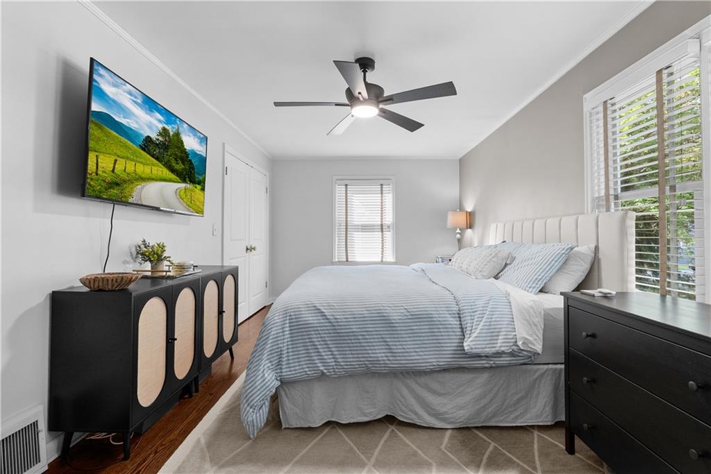 Bedroom with pale blue striped bedding, plantation shutters, and black furniture.