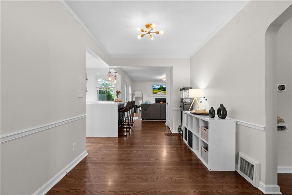 Bright hardwood-floored hallway opening to a kitchen breakfast bar and living room.