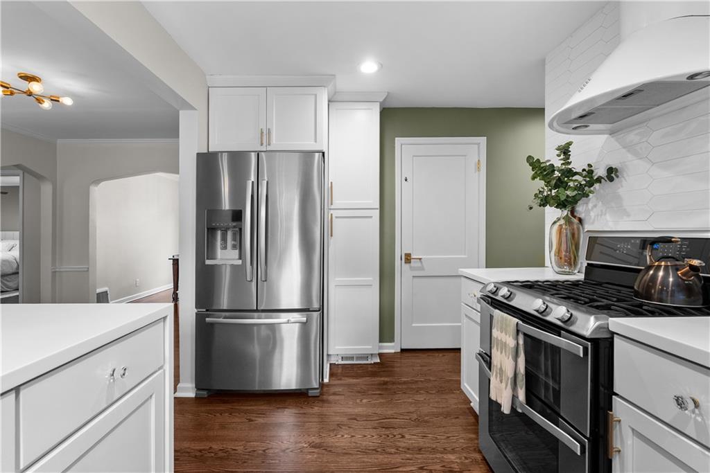 Renovated kitchen with white cabinets, stainless appliances, and a green accent wall.