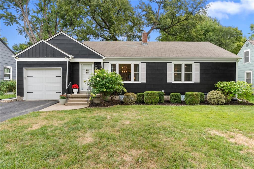 Single-story charcoal house with white trim, an attached garage, and landscaped shrubs.