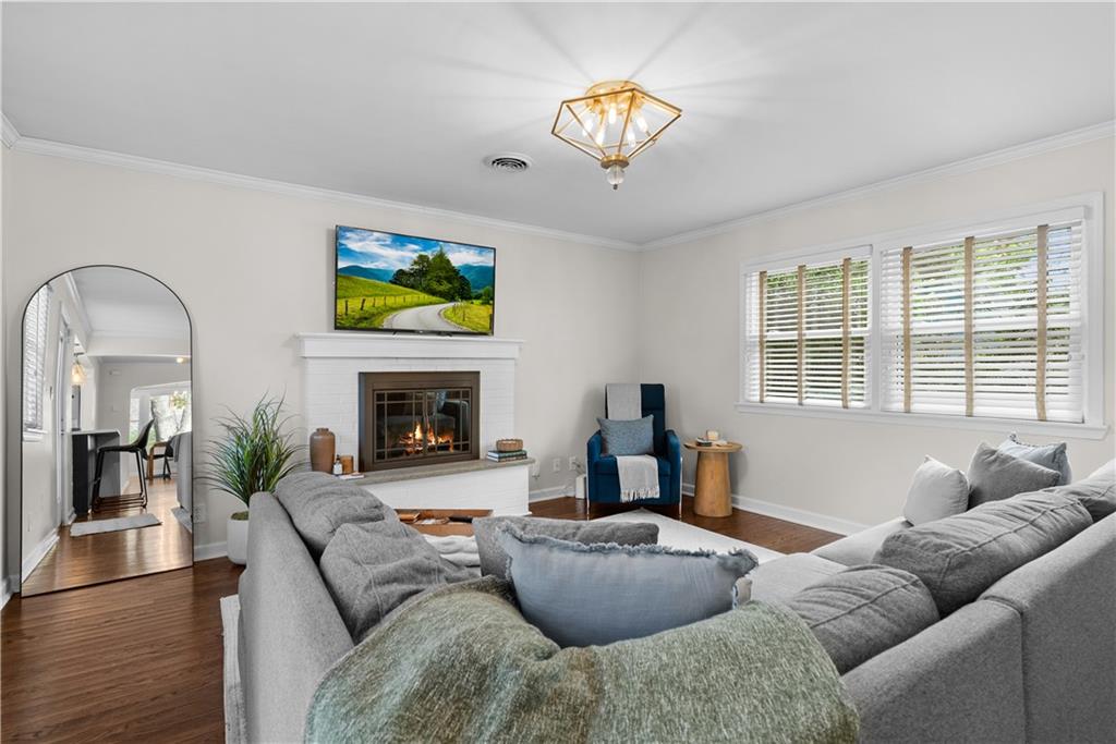 Living room with a gray sectional facing a white brick fireplace and wide windows.