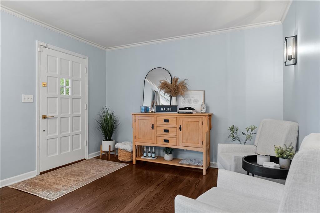 Furnished entryway with a white paneled door, wooden console, arched mirror, and dark hardwood floors.