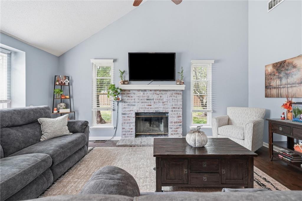 Living room with a whitewashed brick fireplace, vaulted ceiling, and gray sectional sofa.