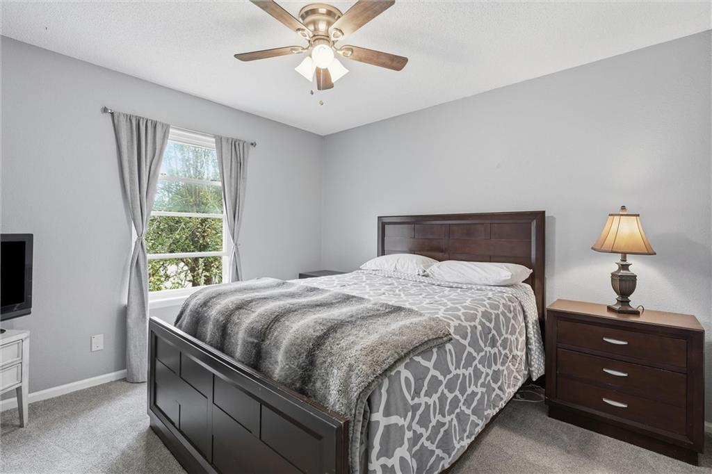 Bedroom with a dark wood bed, gray patterned bedding, and a curtained window.