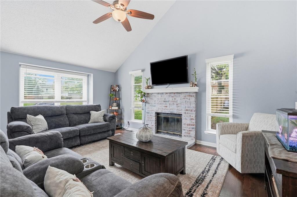 Living room with a brick fireplace, wall-mounted television, and gray sectional sofa.