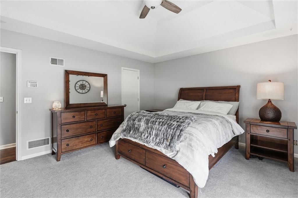 Bedroom with a dark wood bed, white bedding, gray throw, and matching furniture.