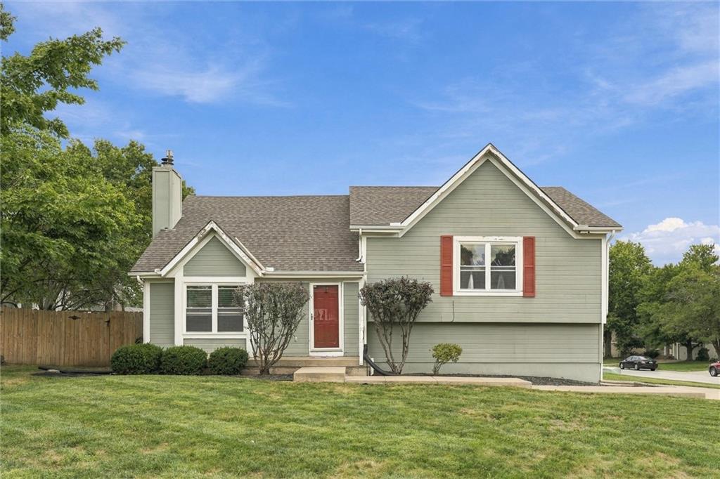 Gray-green house with a red front door and shutters, white trim, and a broad front lawn.