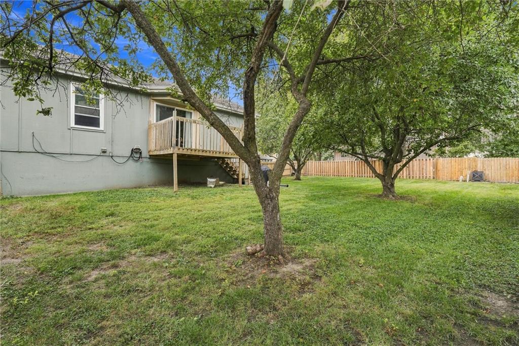 Gray house with a raised wooden deck overlooking a fenced, tree-shaded backyard.
