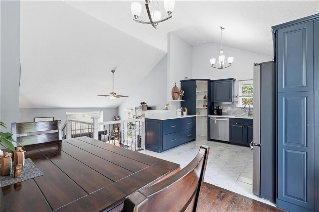 Kitchen and dining area with navy cabinets, marble-look tile flooring, and a dark wood table.