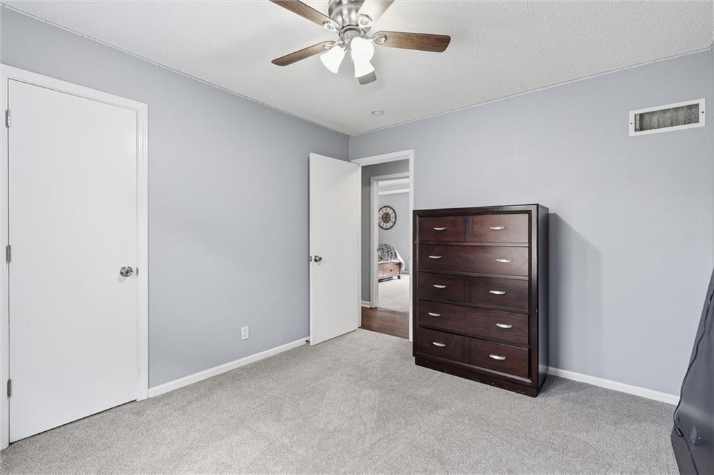 Carpeted bedroom with a dark wood dresser and an open doorway to another room.