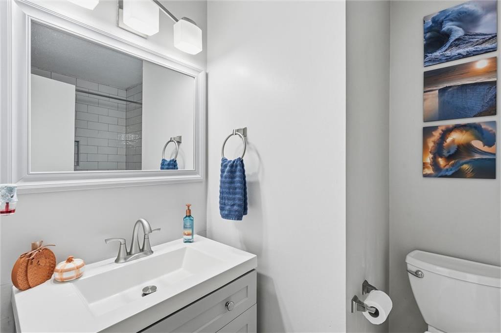 Bathroom with a white vanity, large mirror, toilet, and three ocean-themed wall pictures.