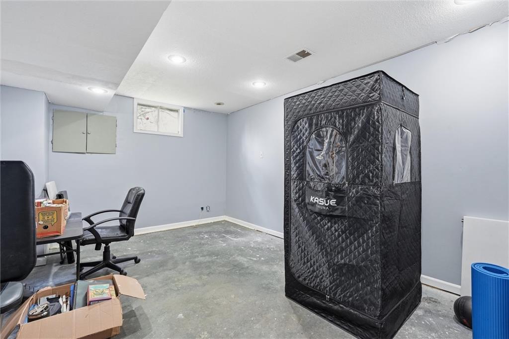 Basement room with a black sauna tent, office chairs, and a concrete floor.