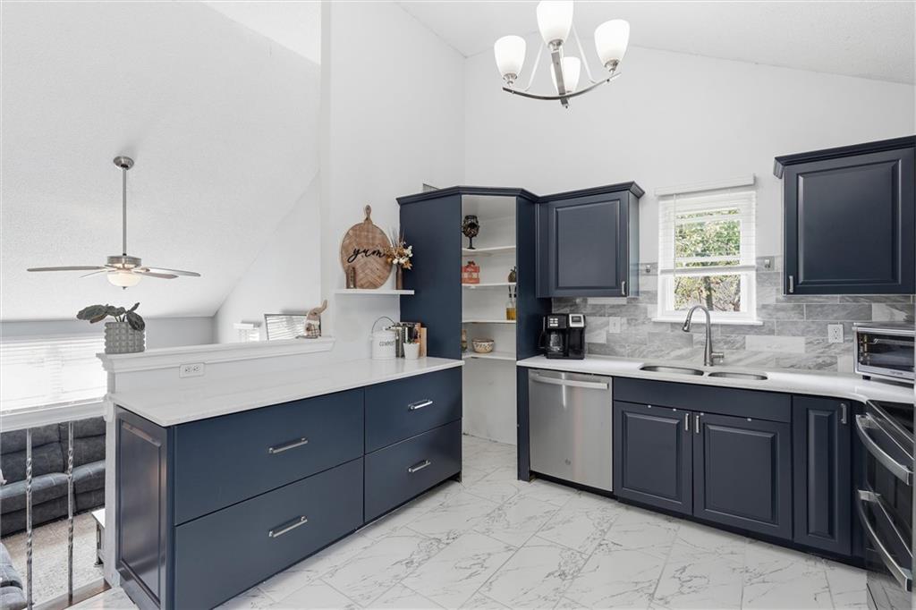 Kitchen with navy cabinets, marble backsplash, stainless steel appliances, and a large peninsula.