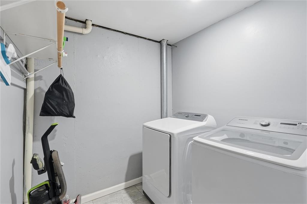 Laundry room with a white washer and dryer, gray tile floor, and wall shelving.