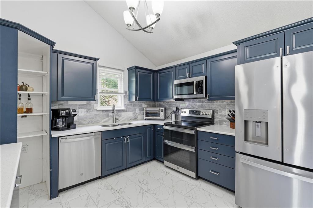 Kitchen with navy cabinets, stainless steel appliances, and marble-look tile flooring.