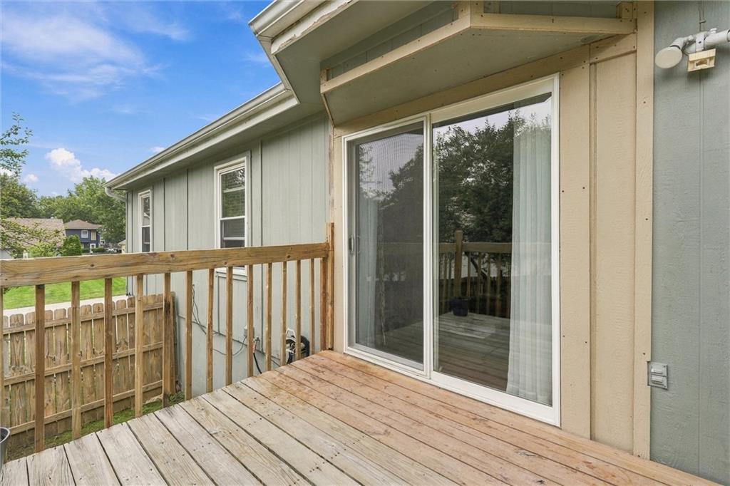 Wooden deck beside sliding glass doors, with a railing overlooking a fenced yard.