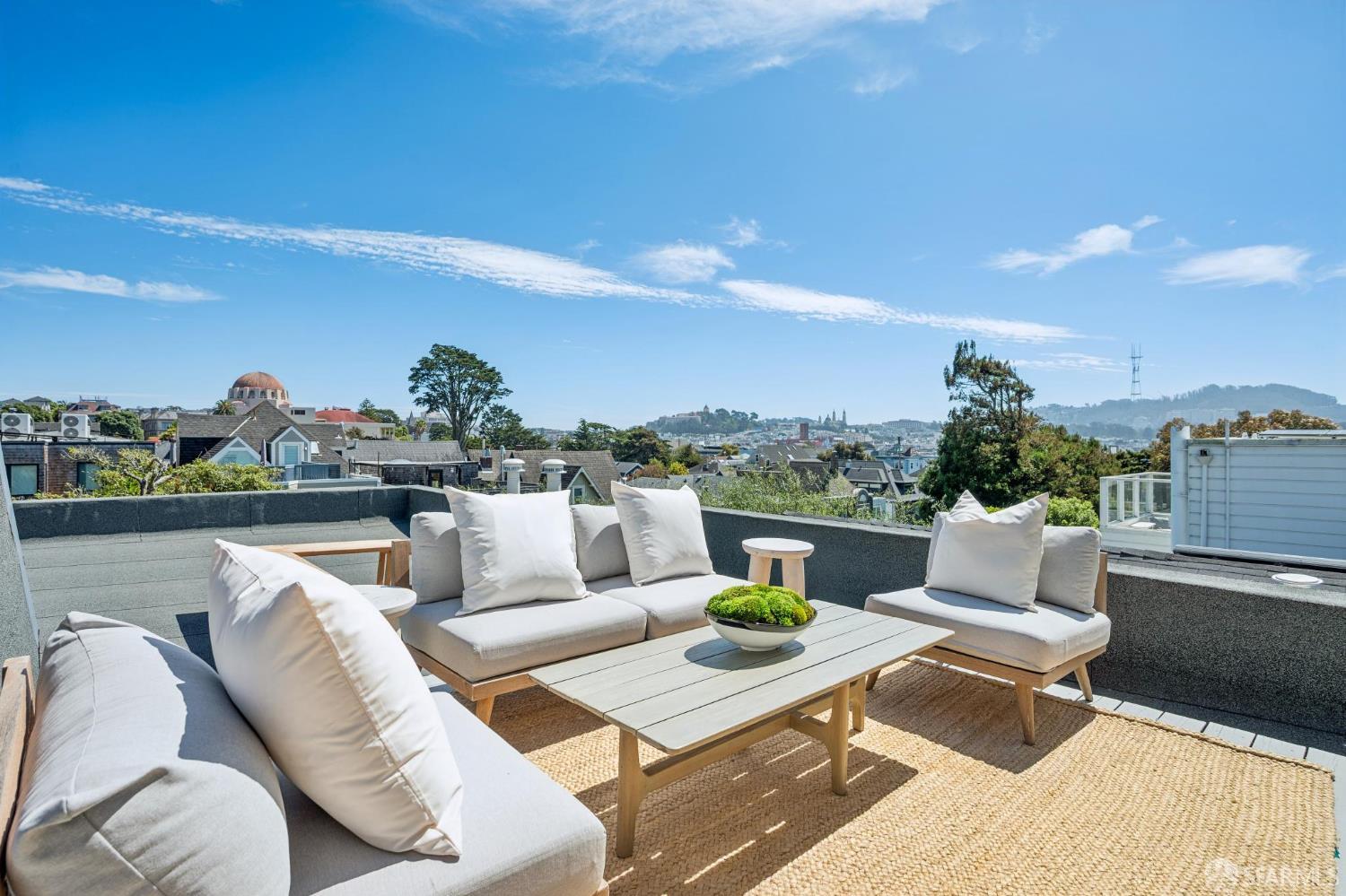 Furnished rooftop terrace with white sofas and a wide view over San Francisco rooftops.