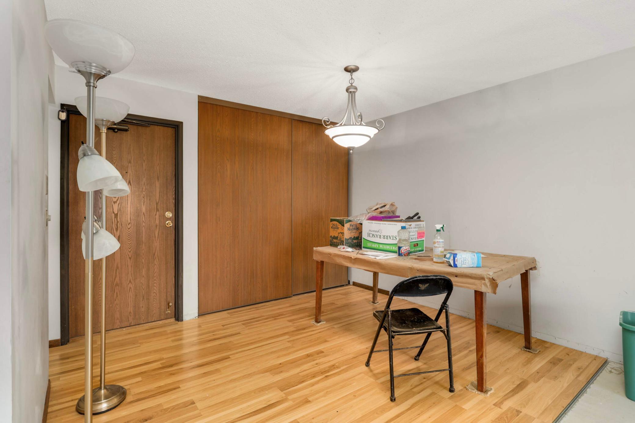Interior room with hardwood floors, sliding wood closet doors, and a table beneath a chandelier.