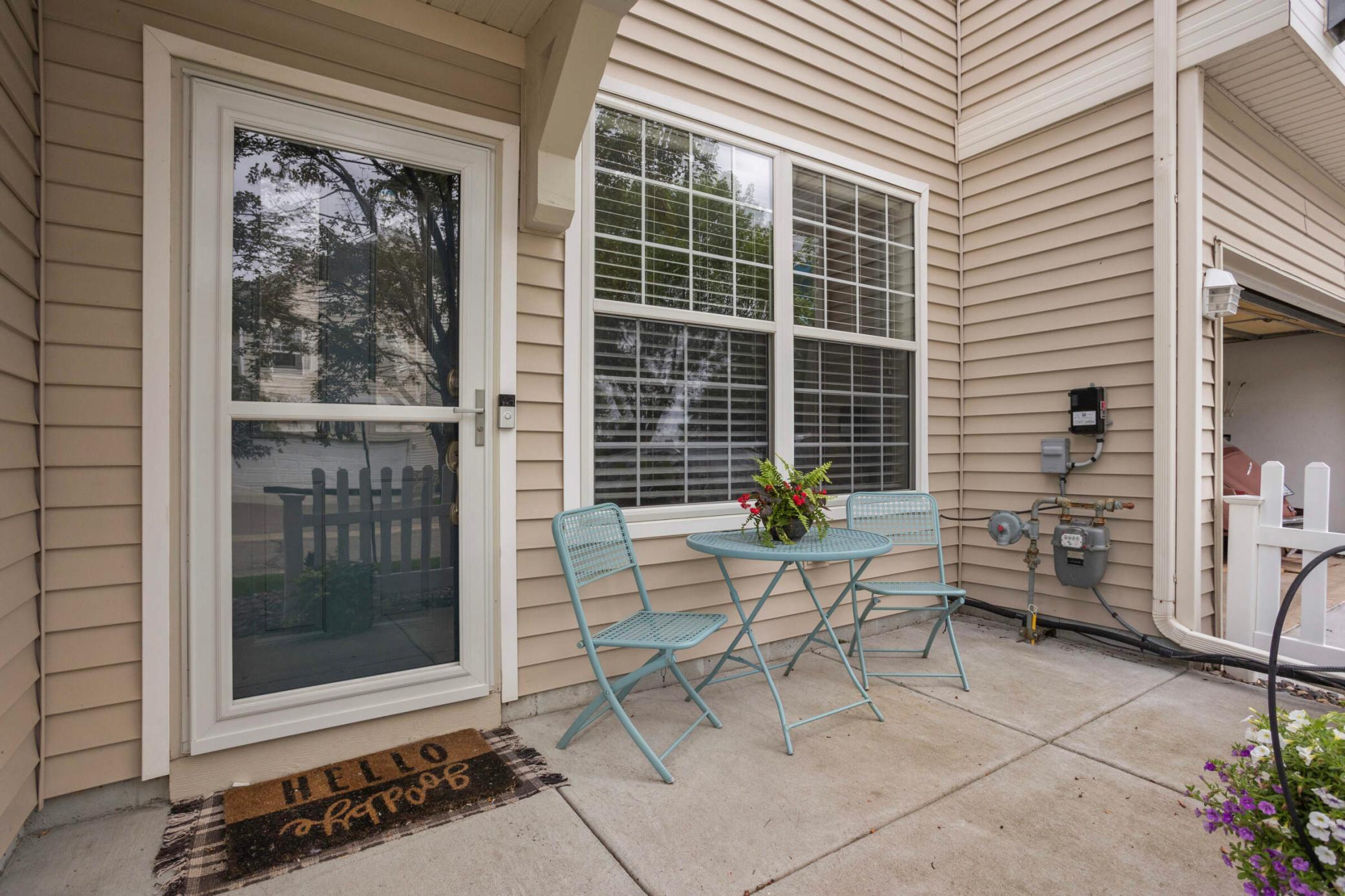 Townhouse patio with turquoise table and chairs beside a glass door and windows.