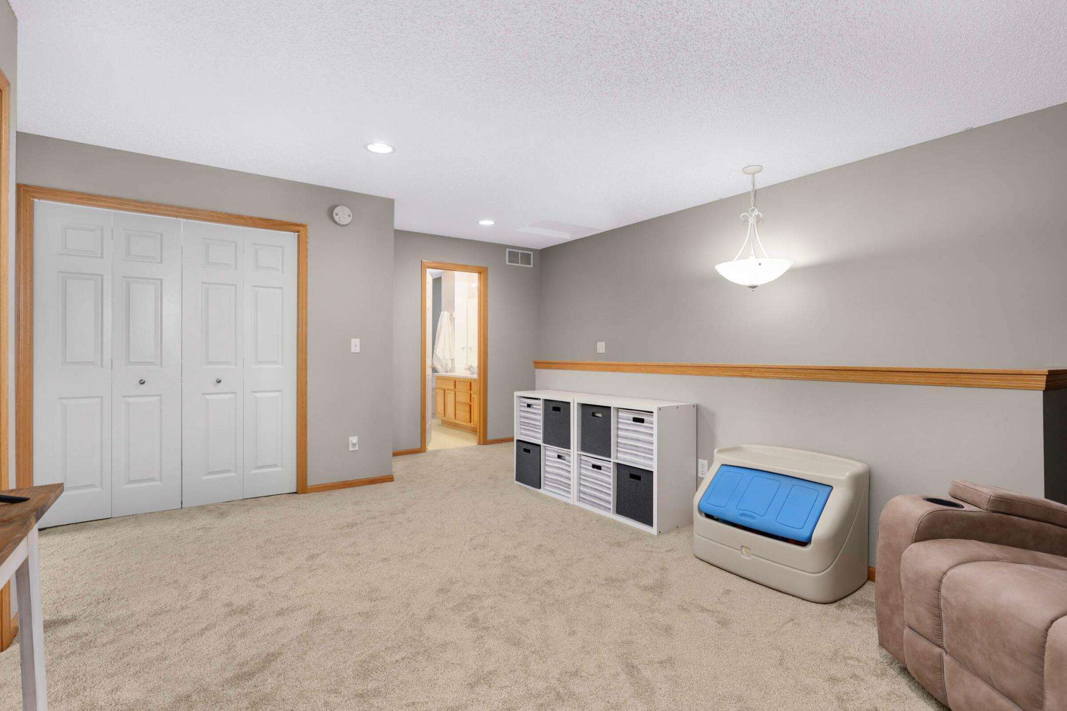 Carpeted room with a four-panel closet, storage cubbies, and an adjoining bathroom doorway.