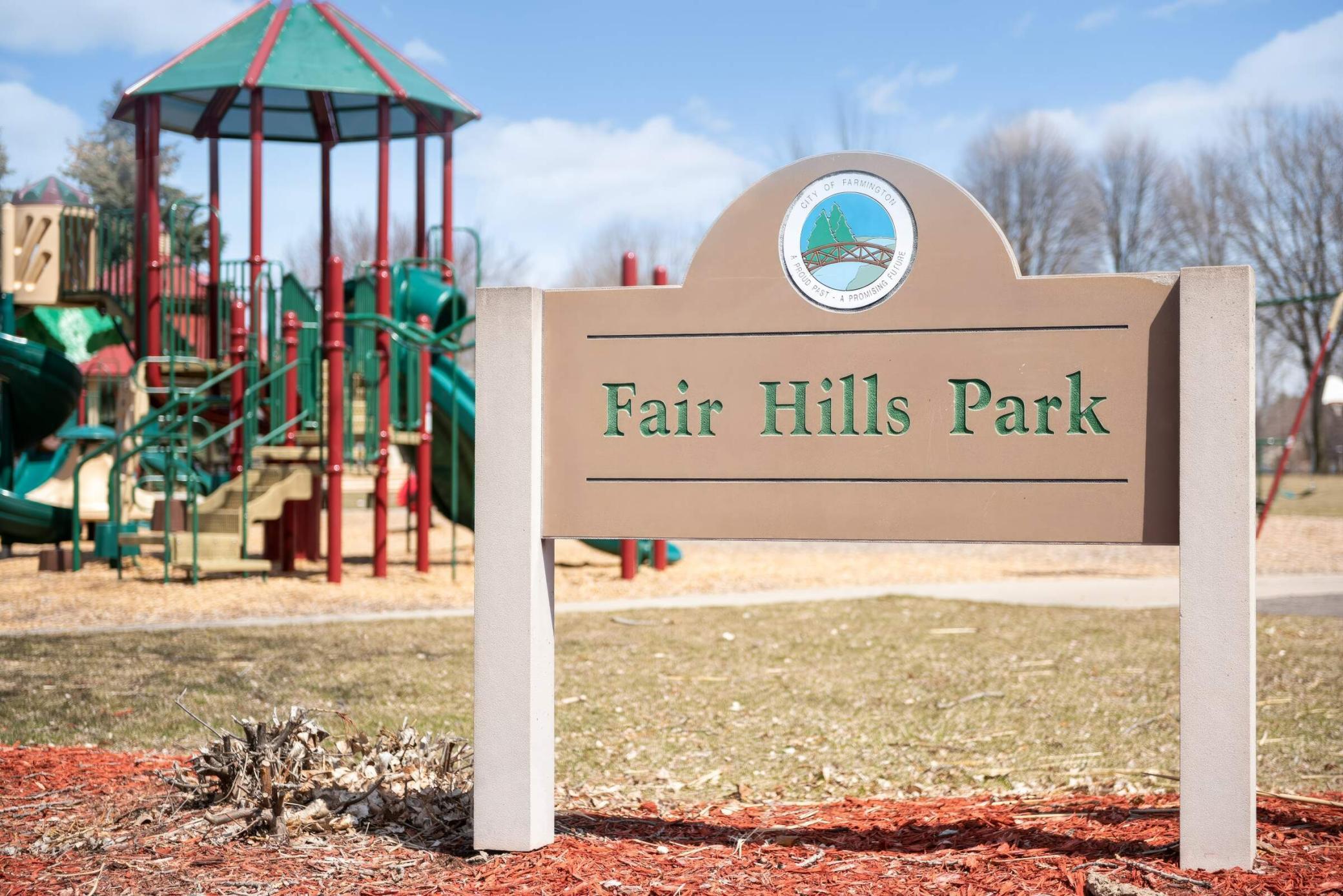 Fair Hills Park sign in front of a colorful playground.