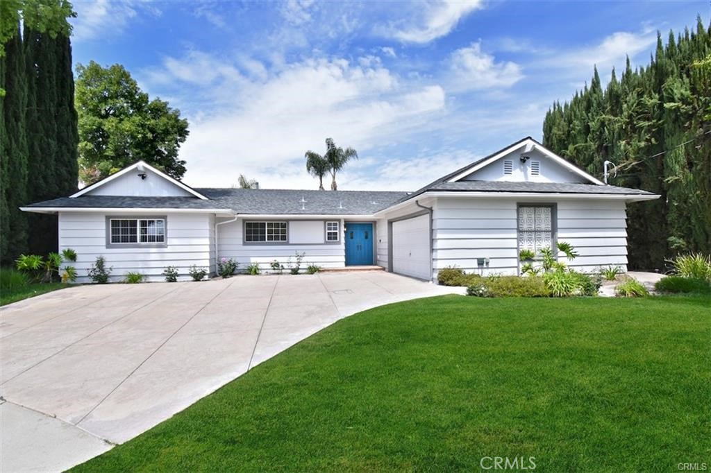 White single-story home with a bright blue front door, attached garage, and broad concrete driveway.