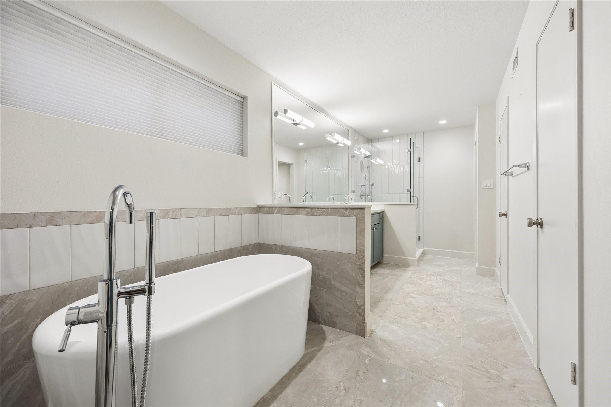 Contemporary bathroom with a freestanding soaking tub, chrome faucet, and glass-enclosed shower.