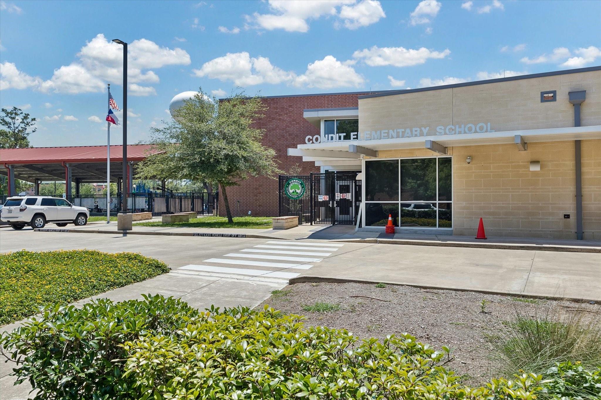 Condit Elementary School entrance with a covered walkway, flags, and a crosswalk.