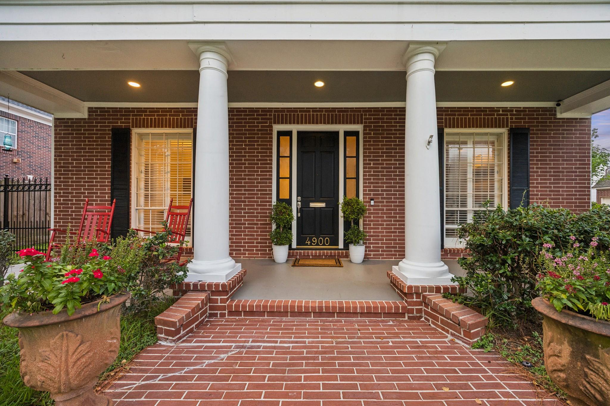 Brick home entrance with white columns, brick steps, and a black door marked 4900.