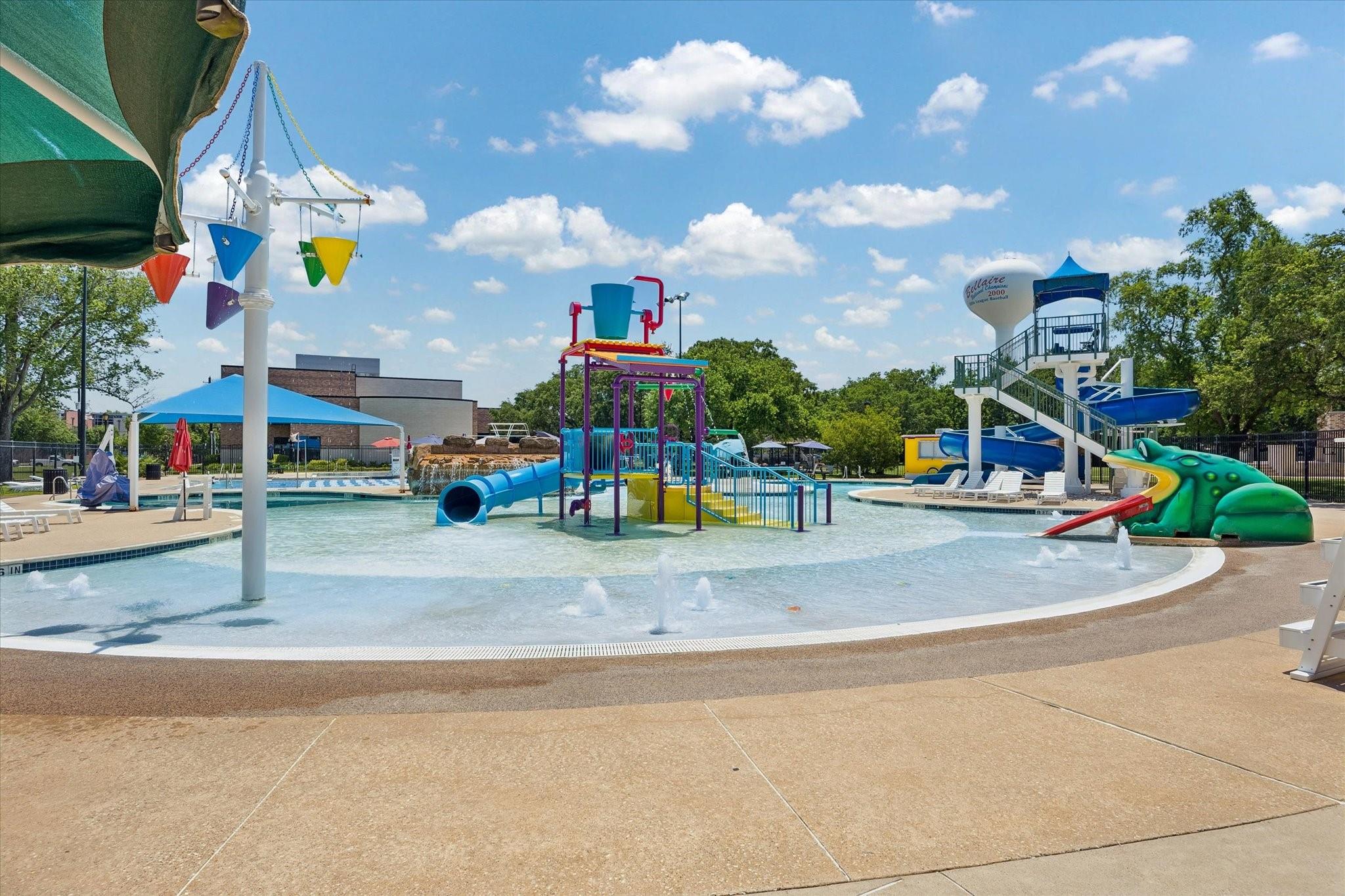 Community pool with colorful splash structures, shallow-water fountains, a green frog feature, and slides.