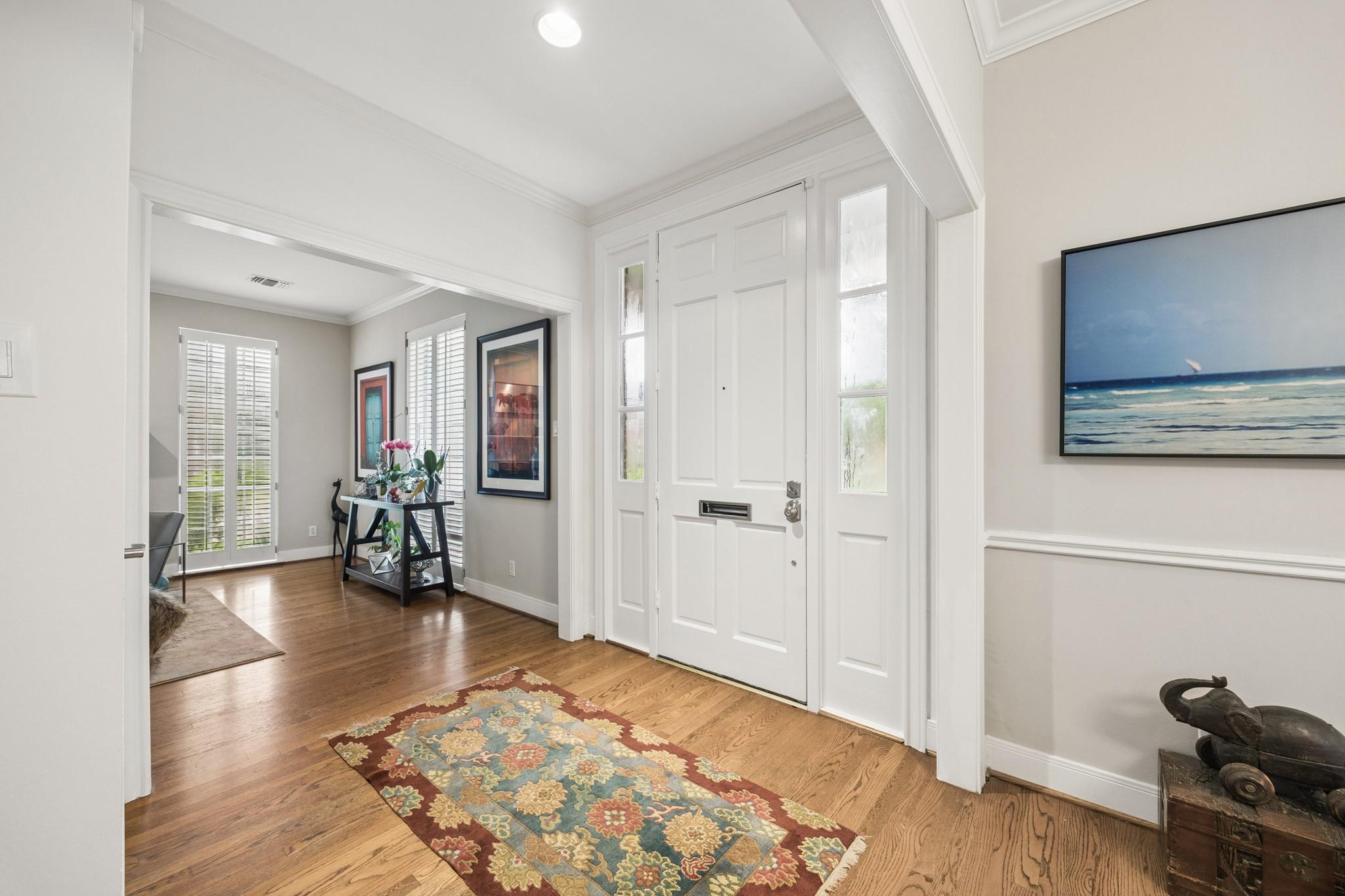 Furnished entryway with a white paneled front door, hardwood floors, and a colorful patterned runner rug.