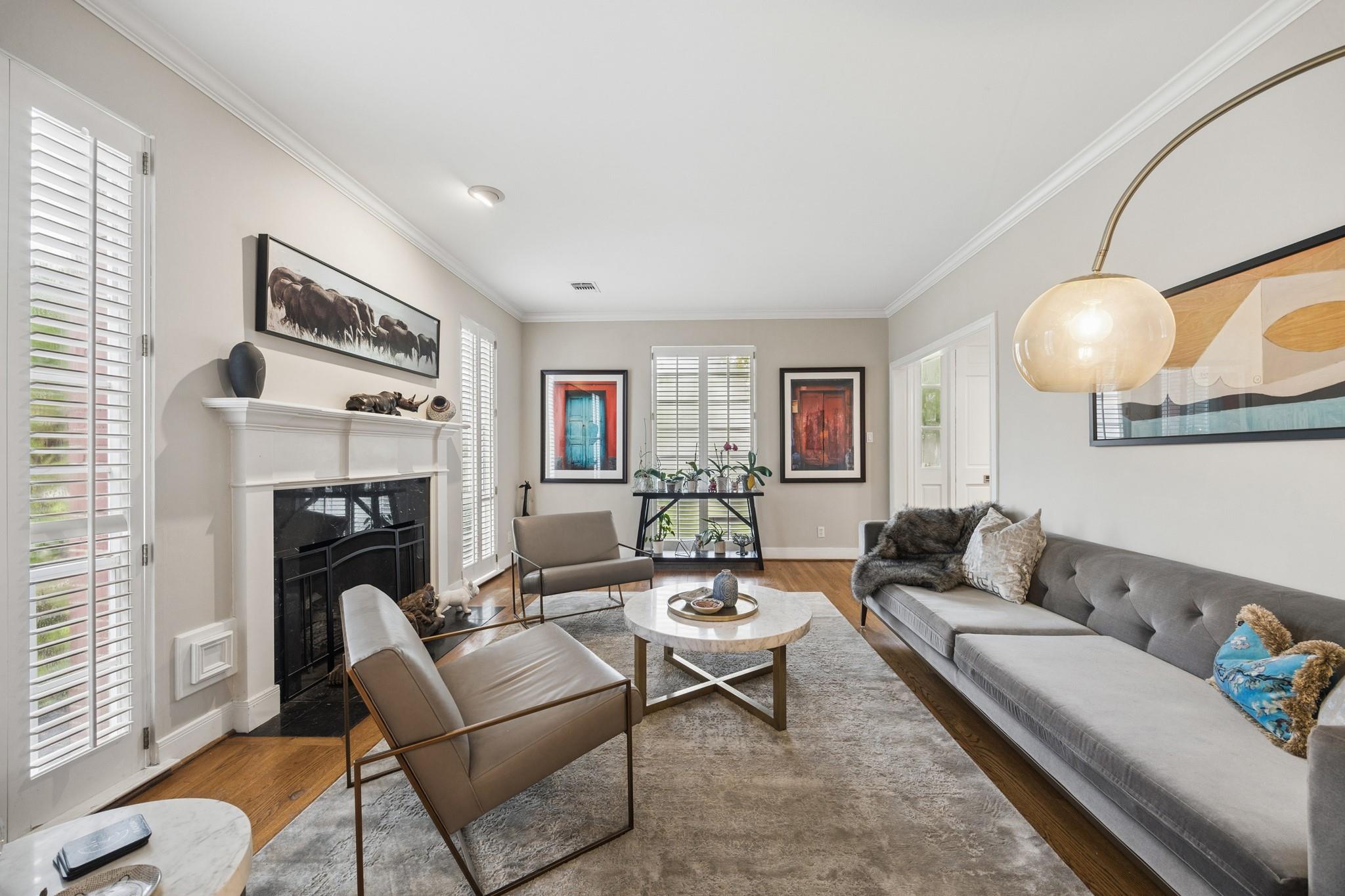 Furnished living room with a white fireplace, plantation shutters, and a long gray sectional sofa.