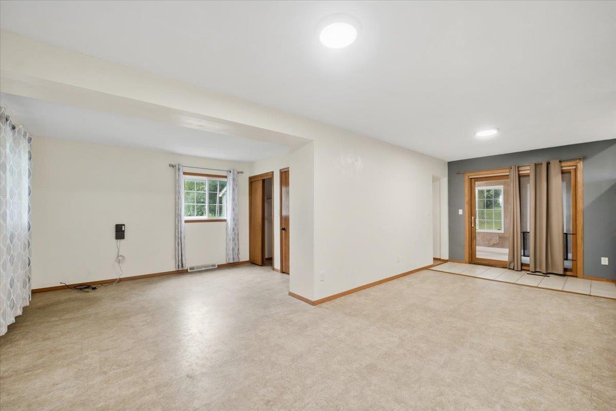Vacant living area with beige flooring and wood-framed glass doors to a patio.