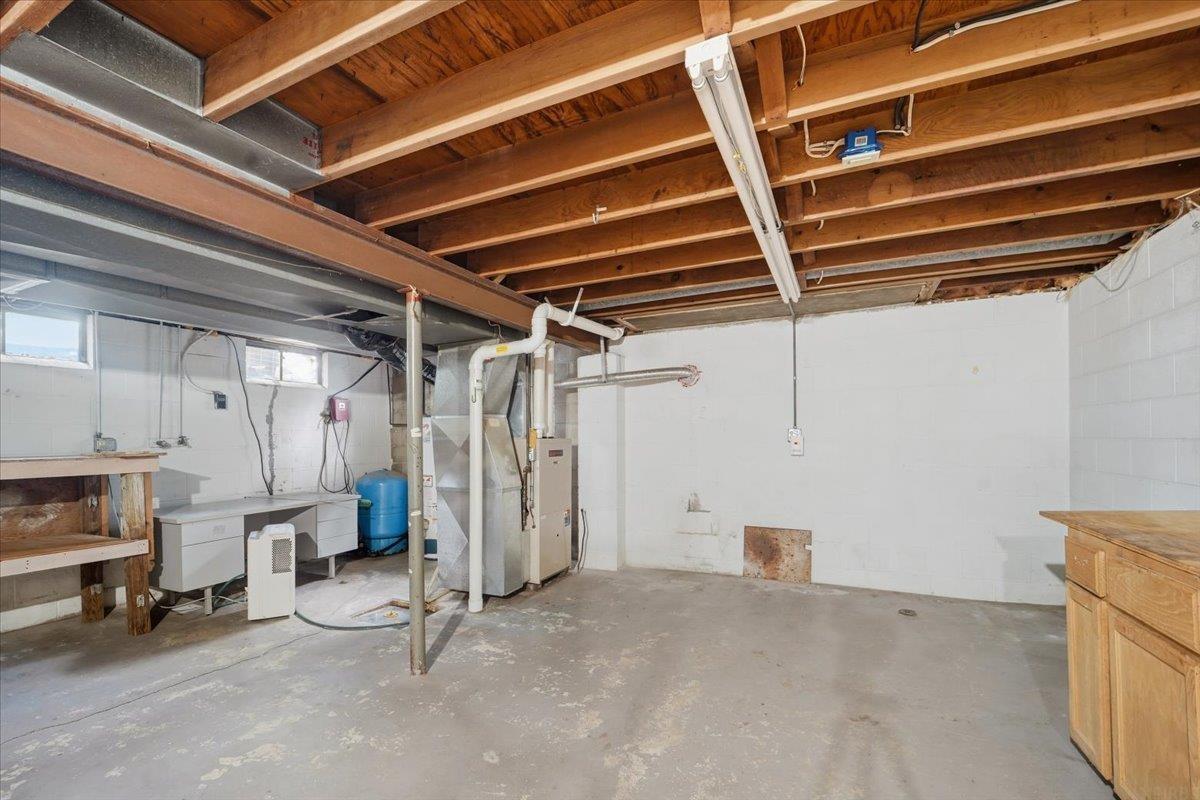 Unfinished basement utility room with exposed joists, mechanical equipment, and a concrete floor.