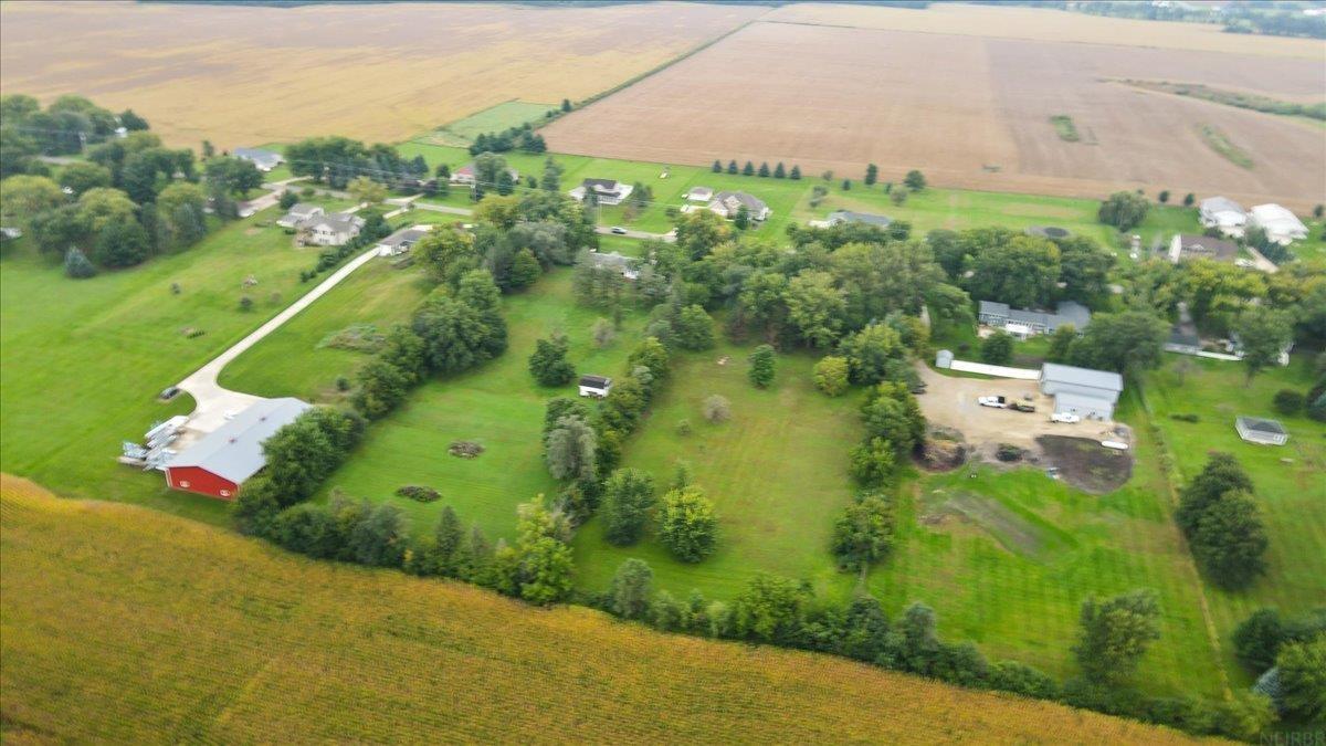 Aerial view of rural acreage with crop fields, scattered trees, a long driveway, and outbuildings.