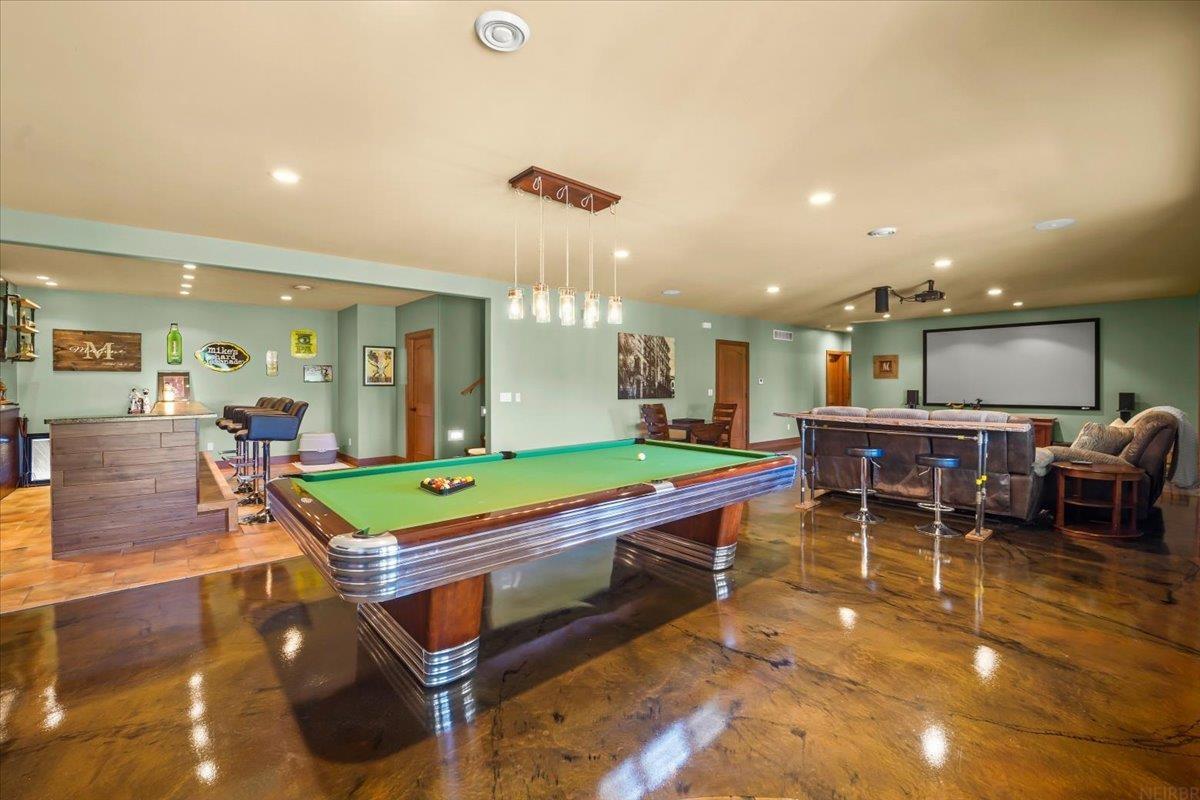 Furnished game room with a green-felt pool table, bar, and projection screen.