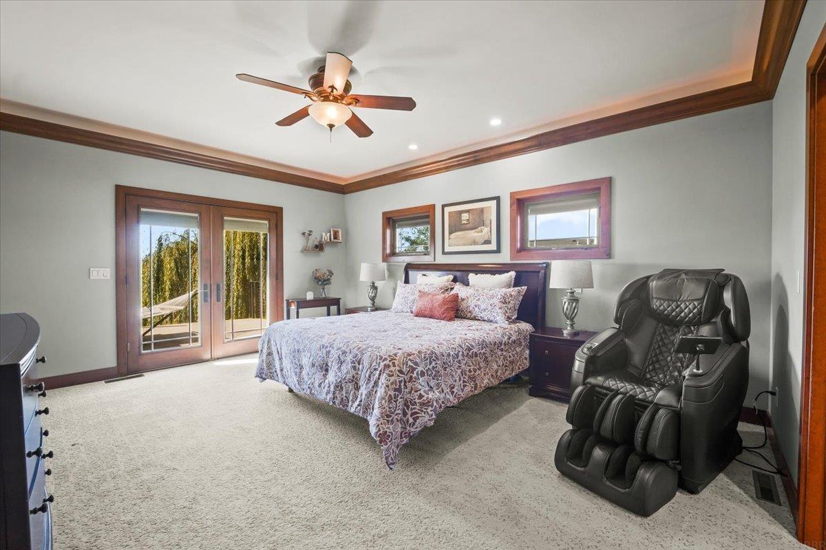 Bedroom with French doors to a balcony and a black massage chair beside the bed.