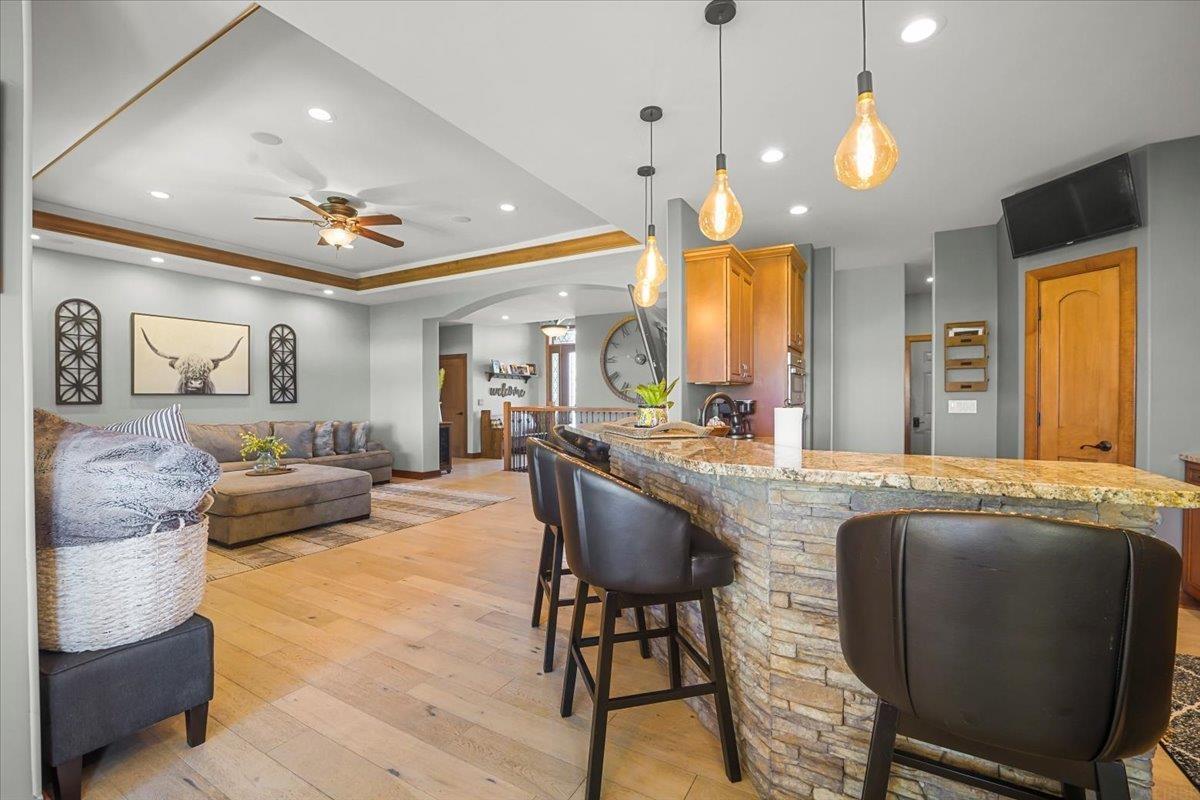 Open-plan kitchen and living room with a stone breakfast bar, granite counter, and gray sectional.