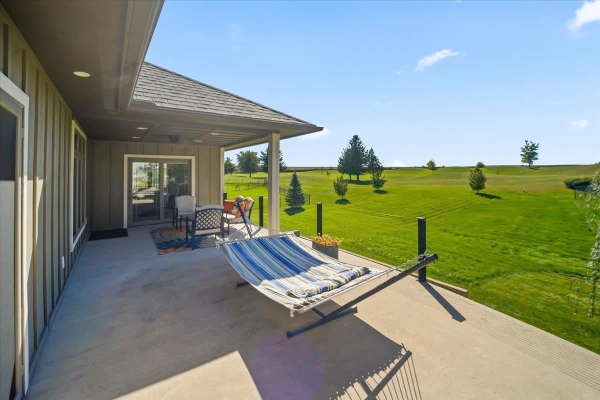 Patio with a striped hammock and seating overlooking a broad green lawn.