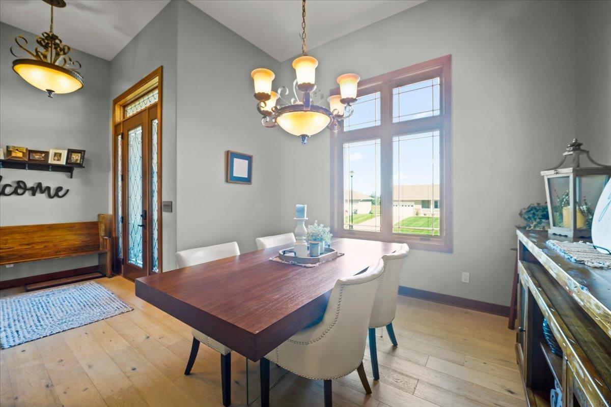 Dining room with a dark wood table, white chairs, and a large window overlooking neighboring homes.