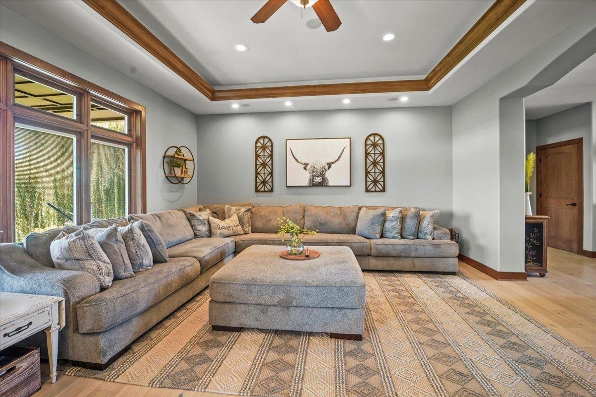 Living room with a gray sectional, matching ottoman, patterned rug, and wood-trimmed tray ceiling.