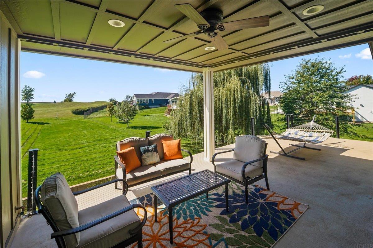 Covered patio with outdoor seating and a hammock overlooking a broad green lawn.