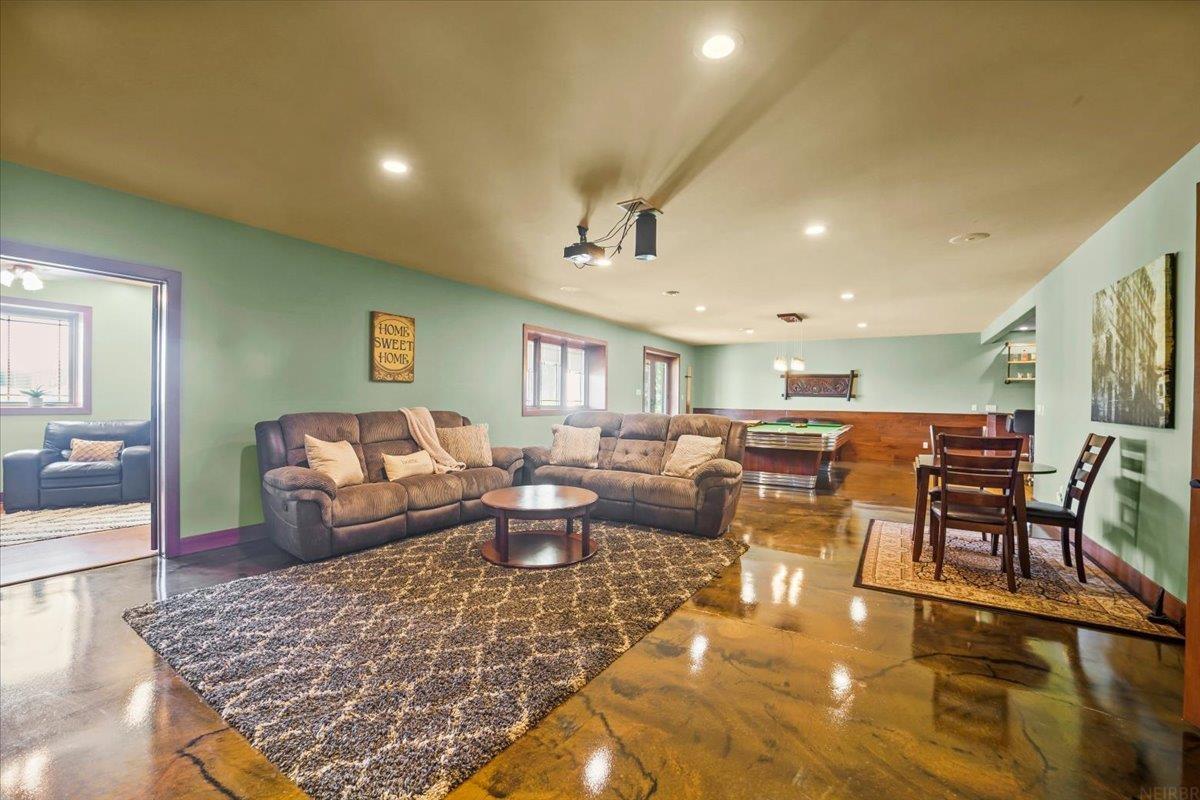 Living room with brown sectional sofas, polished concrete floors, and a pool table.