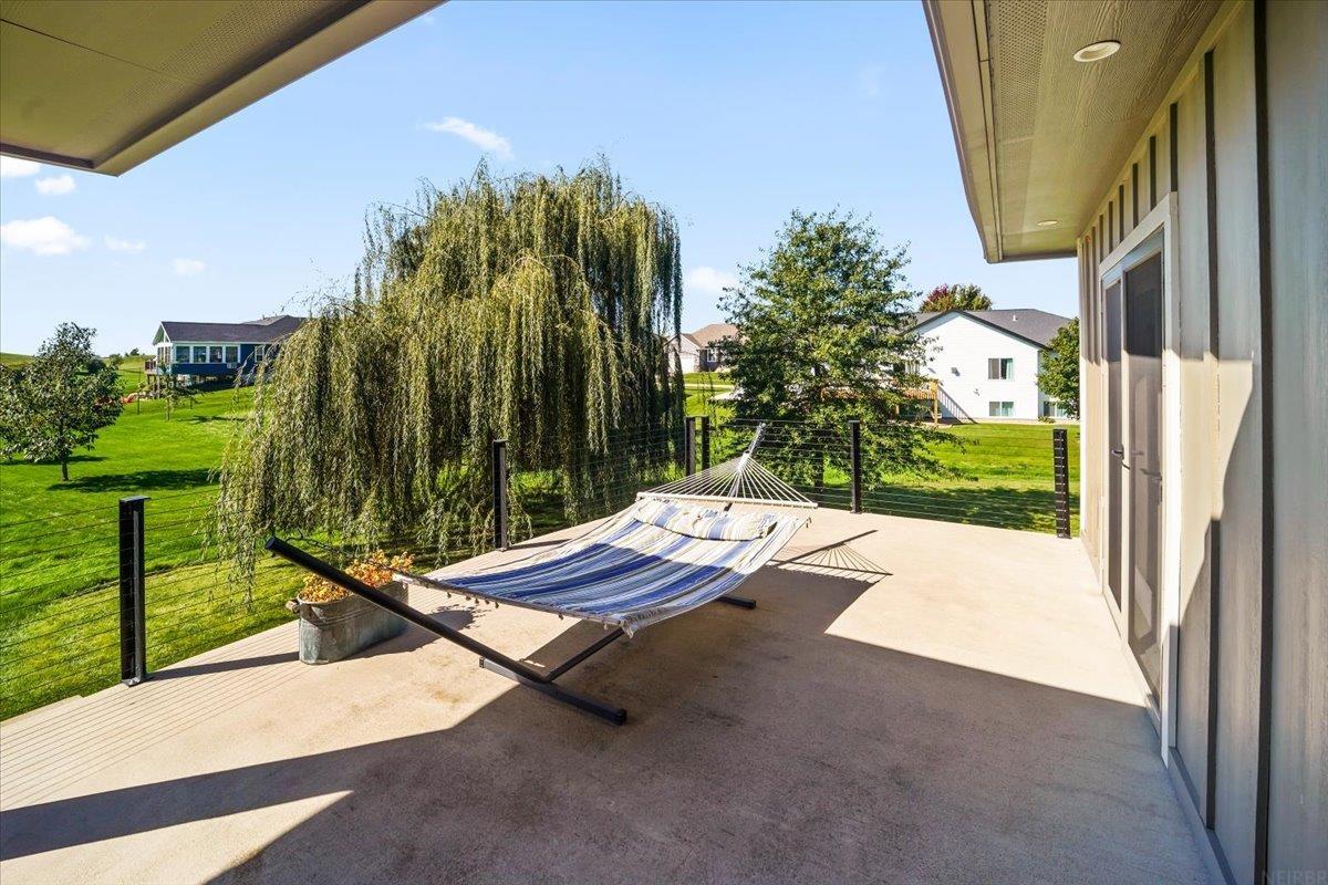 Covered patio with a striped hammock overlooking a weeping willow and neighboring homes.