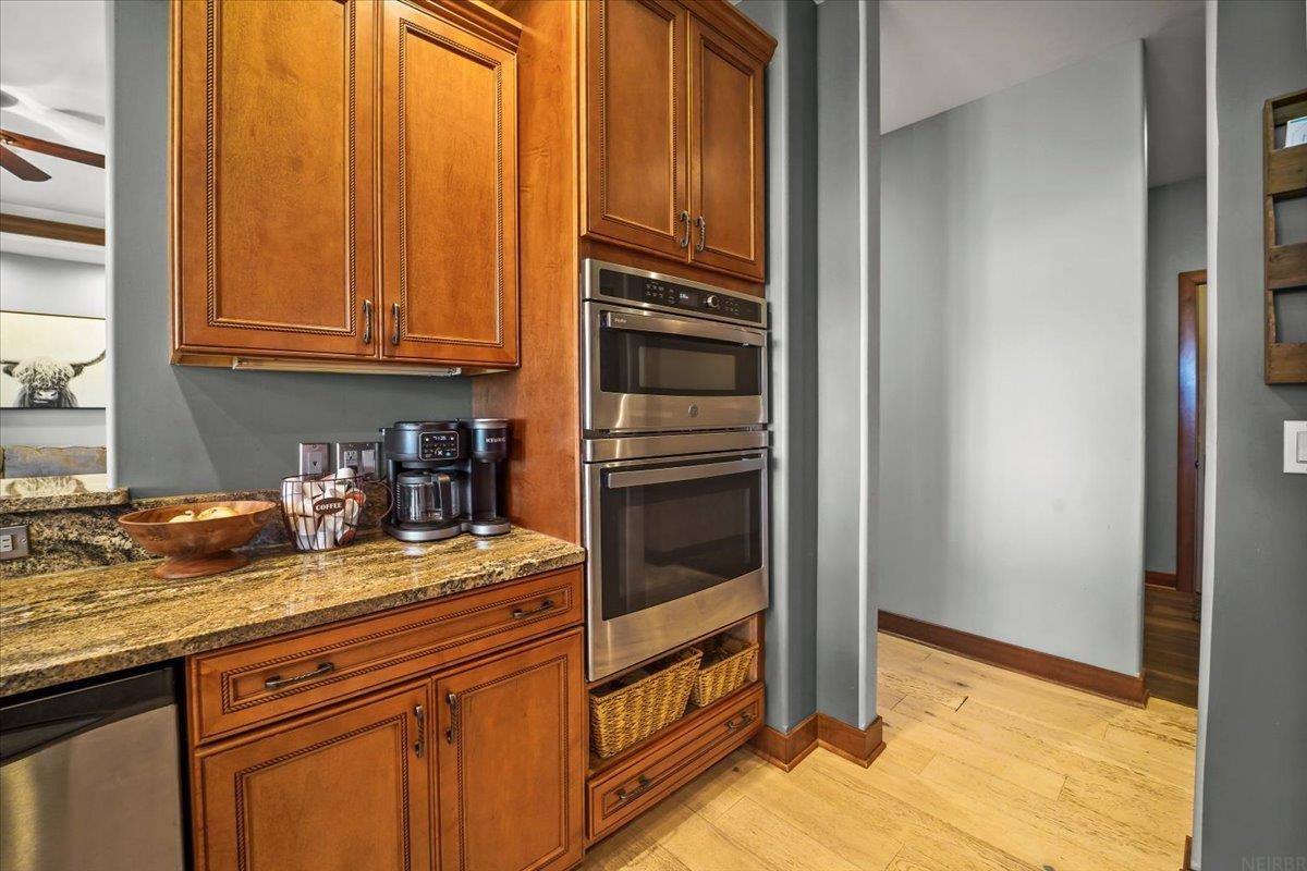 Kitchen with wood cabinetry, granite counters, and stainless steel double wall ovens.