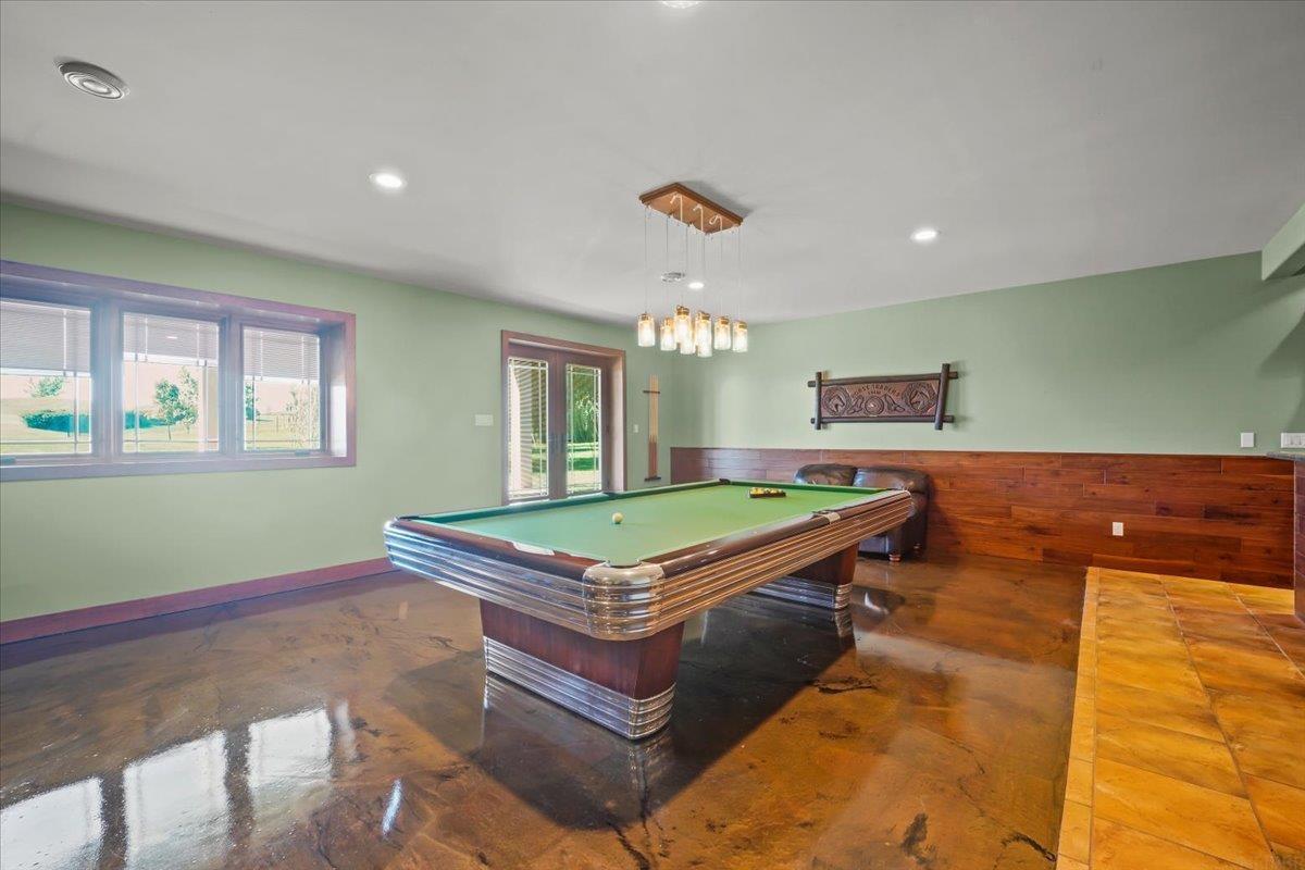 Recreation room with a green-felt pool table and polished concrete floor.