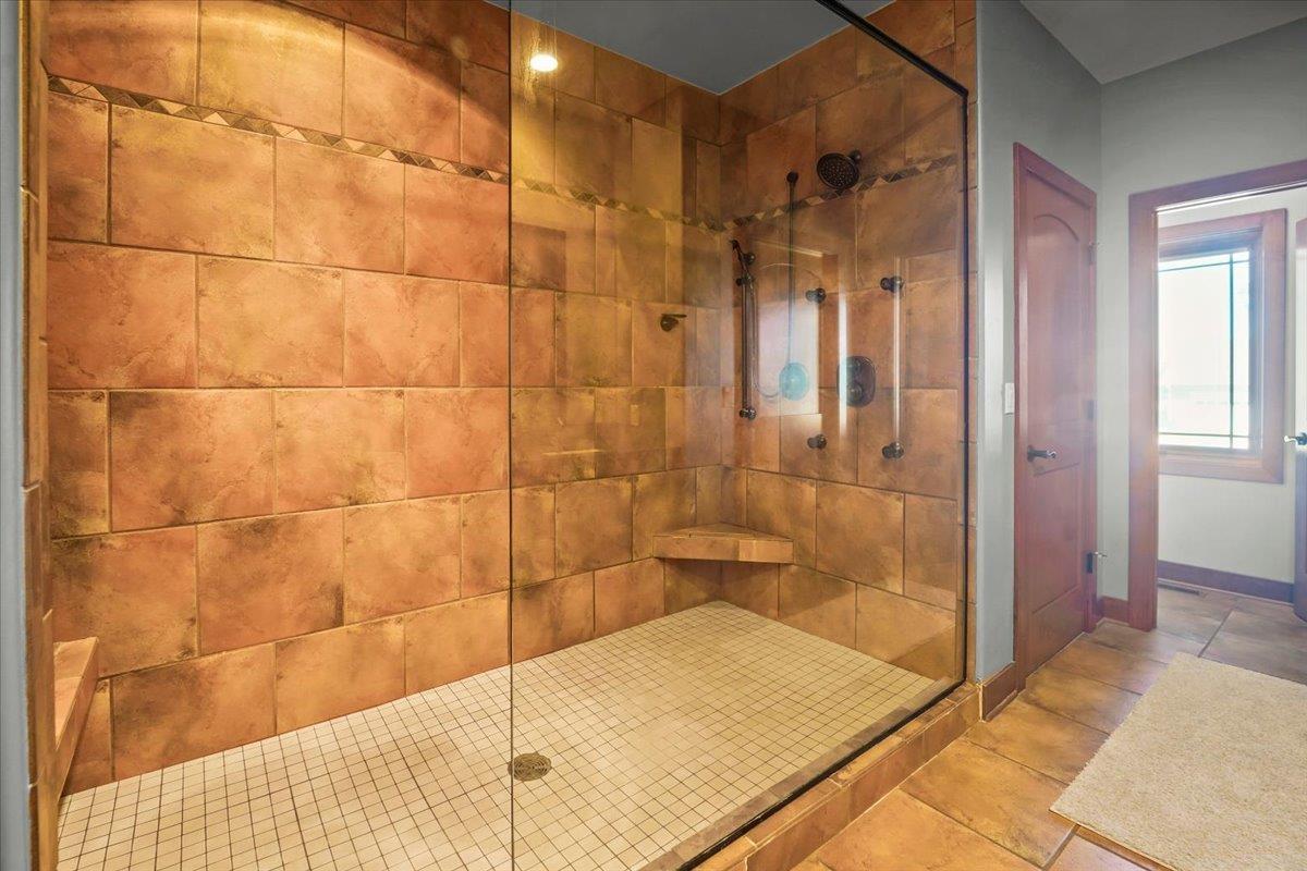 Walk-in shower with warm terracotta tile walls, a built-in bench, and glass enclosure.