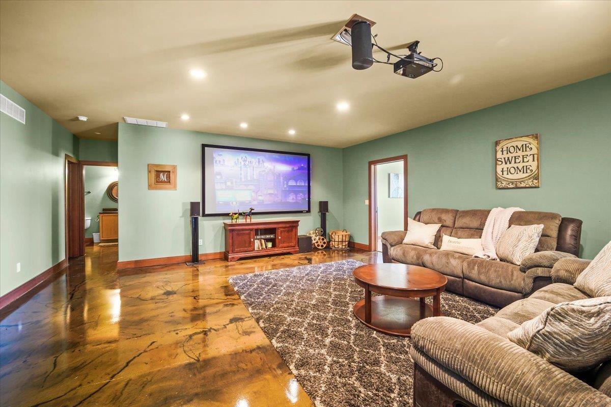 Media room with a large projection screen, brown sectional seating, and polished patterned flooring.